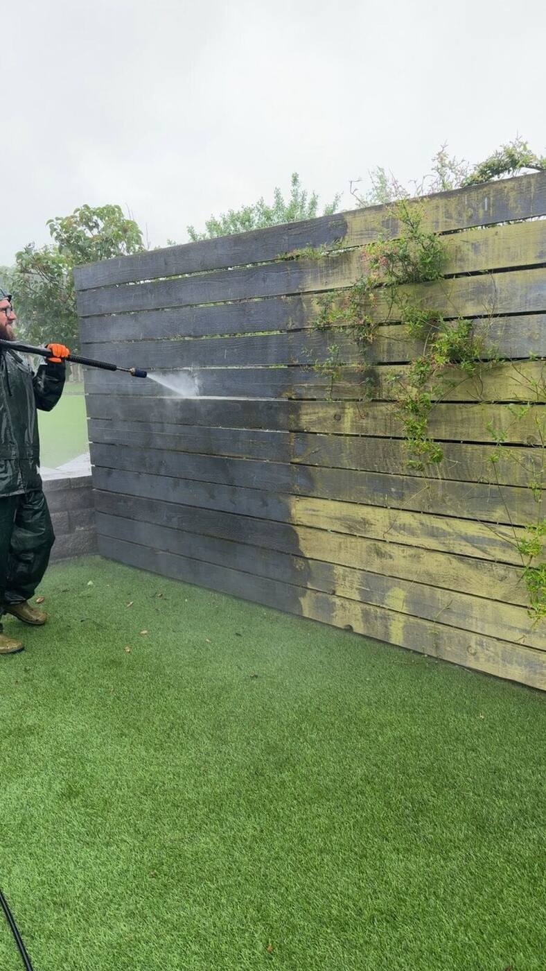 Timber fence half way through cleaning, one side bright and one side green